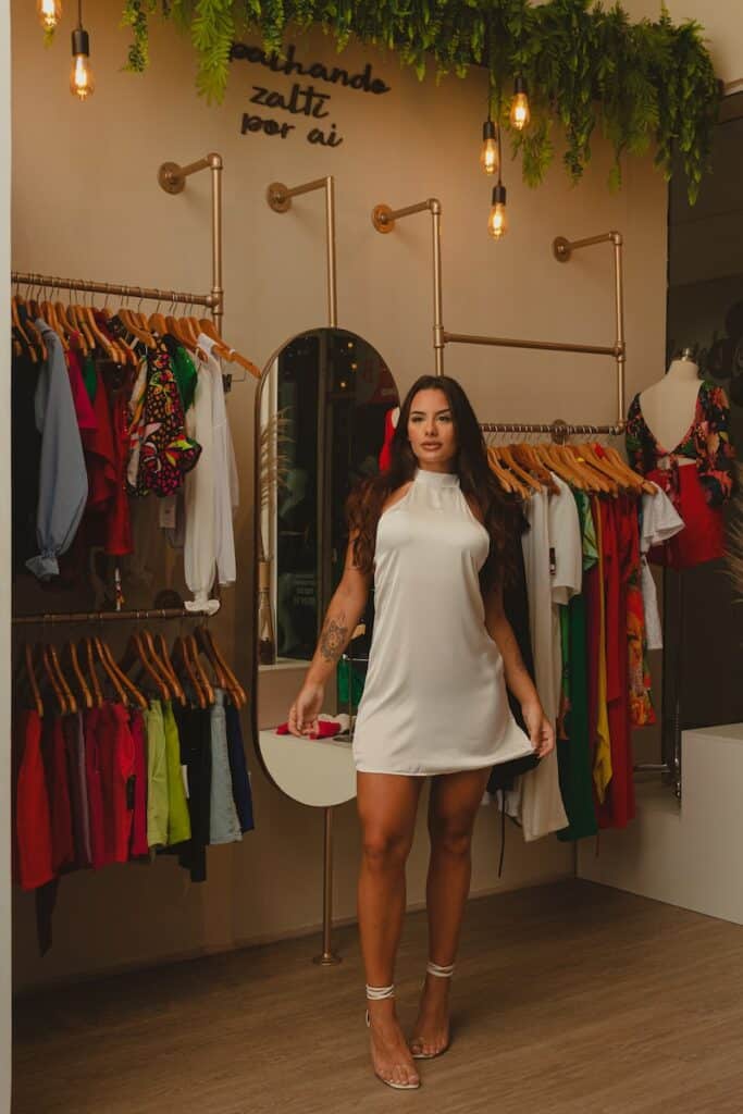 a woman standing in front of a mirror in a clothing store
